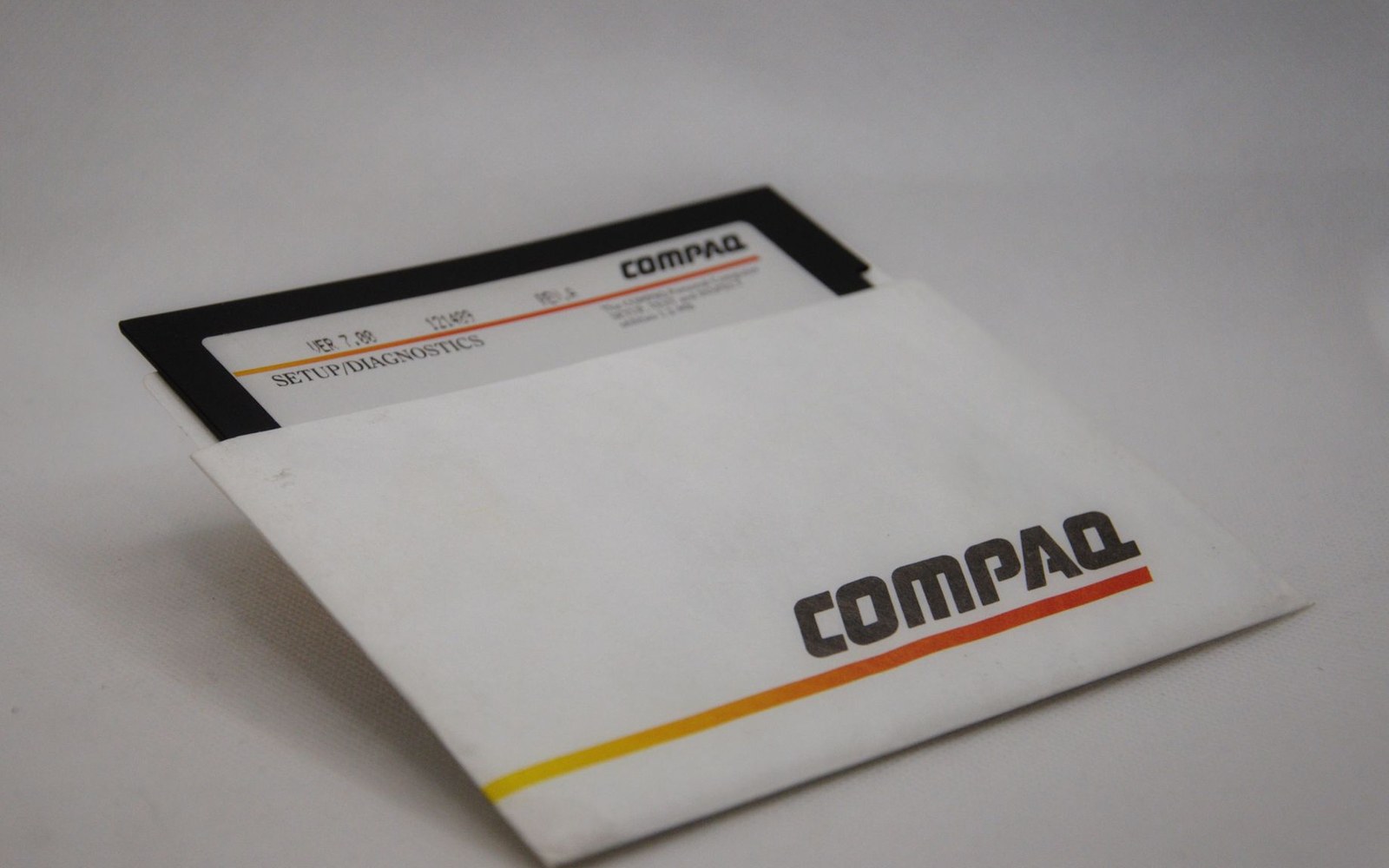 A Compaq setup and diagnostics floppy disk partially pulled from its labeled paper sleeve