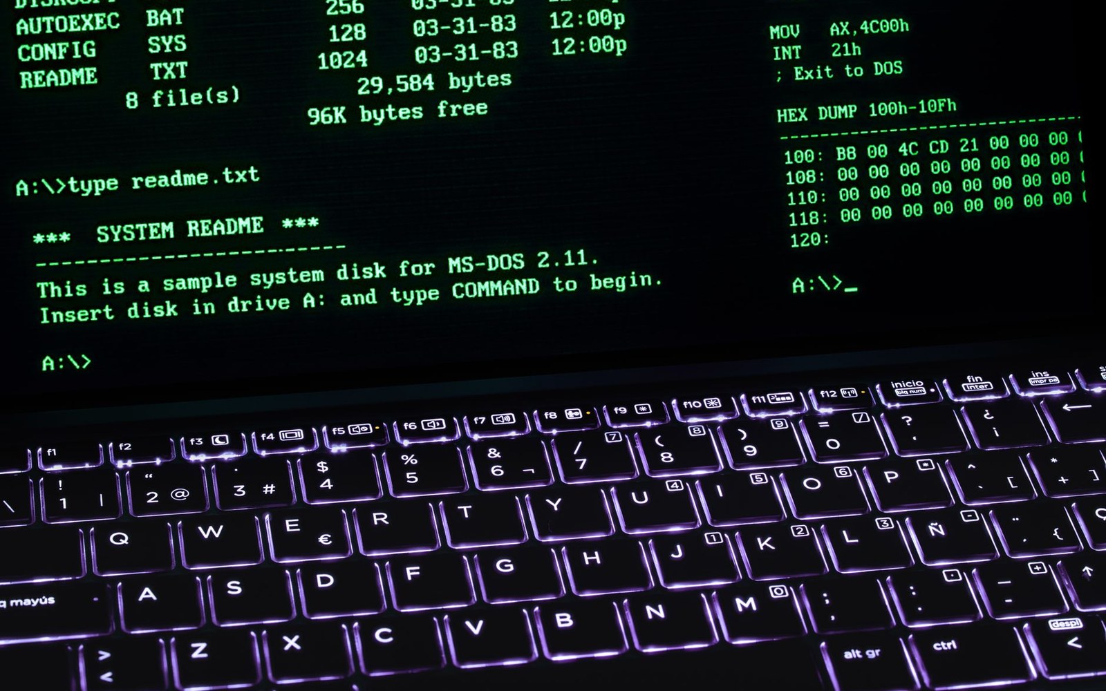 Green MS-DOS command line text glows above a backlit laptop keyboard