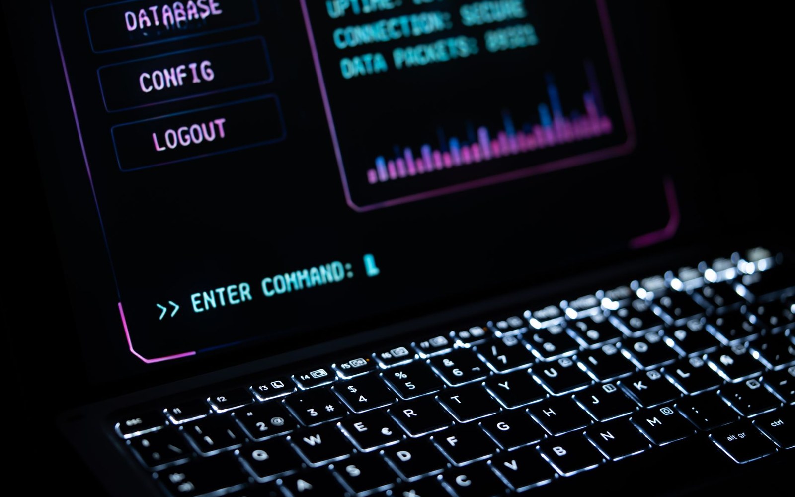 An open sticker-covered laptop on a wooden table, the screen showing a terminal prompt, an adult's hands on the keyboard partially visible at the bottom of the frame